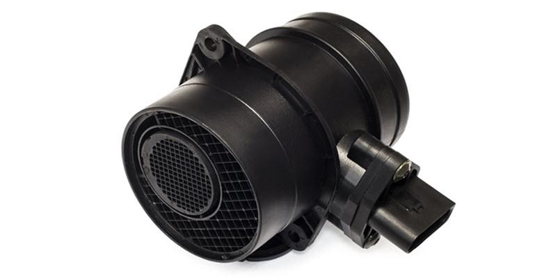 A black mass air flow (MAF) sensor with a cylindrical housing and an electrical connector on the side.