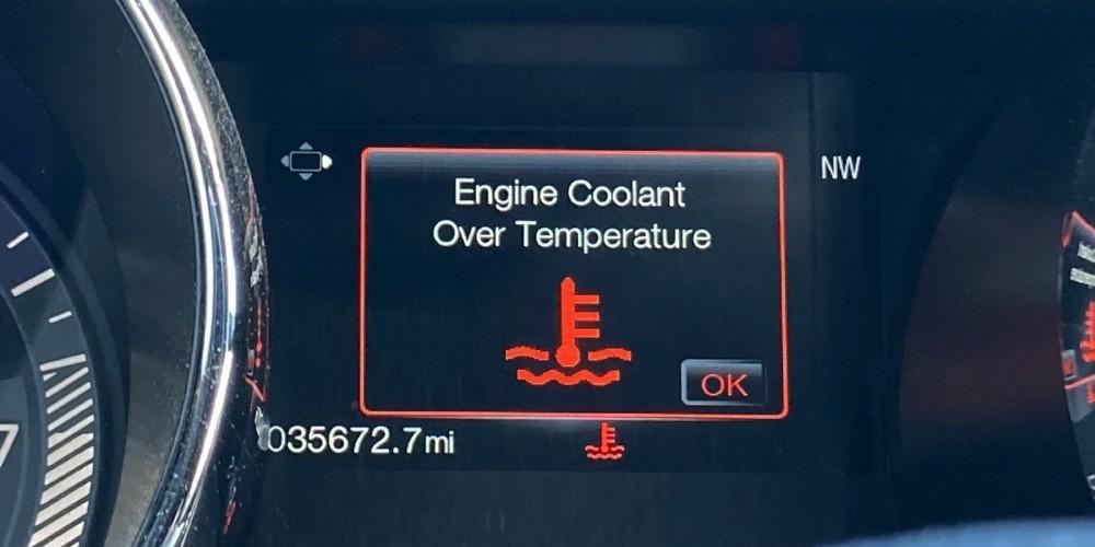 Vehicle dashboard display showing a warning message "Engine Coolant Over Temperature" with a coolant warning icon.