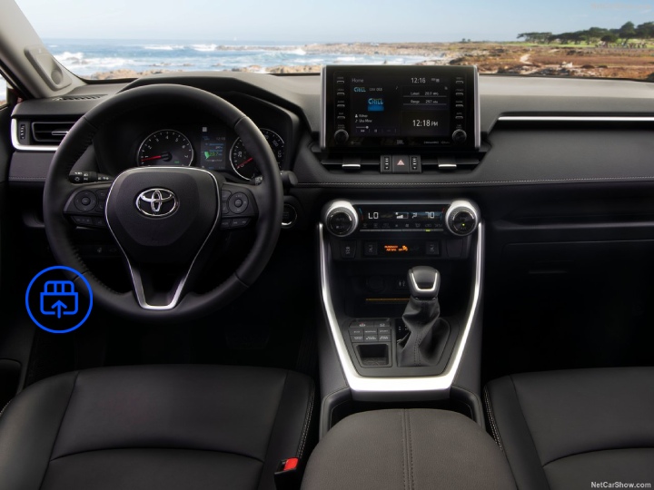  The image shows the interior of a Toyota RAV4, highlighting the OBD-II port location beneath the dashboard near the driver’s footwell.