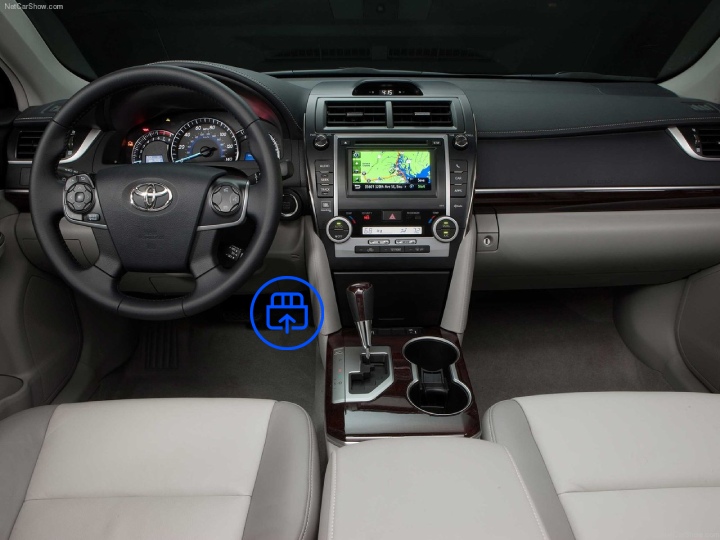  The image shows the interior of a Toyota Camry, highlighting the OBD-II port location beneath the dashboard near the driver’s footwell.