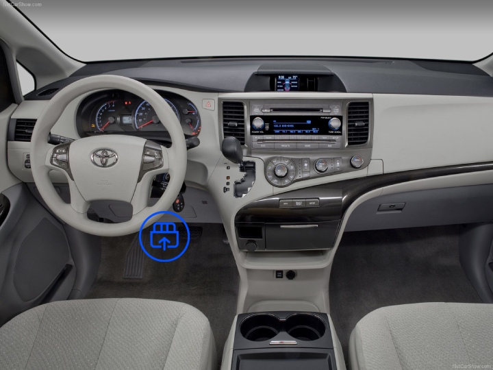  The image shows the interior of a Toyota Sienna, highlighting the OBD-II port location beneath the dashboard near the driver’s footwell.